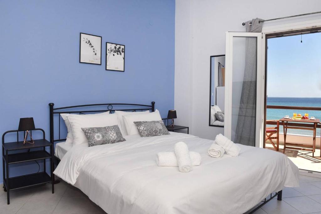 1 dormitorio con cama blanca y vistas al océano en Aegean View Studio #1, en Azolimnos