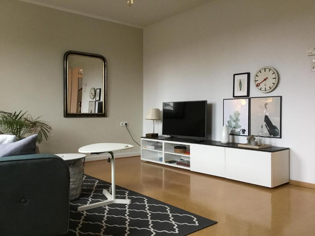 uma sala de estar com uma televisão, uma mesa e um espelho em Wohlfühlambiente in Dorsten em Dorsten