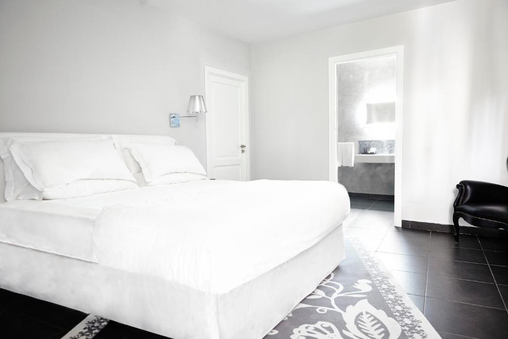 a white bed in a room with a black chair at La Suite Boutique Hotel in Procida