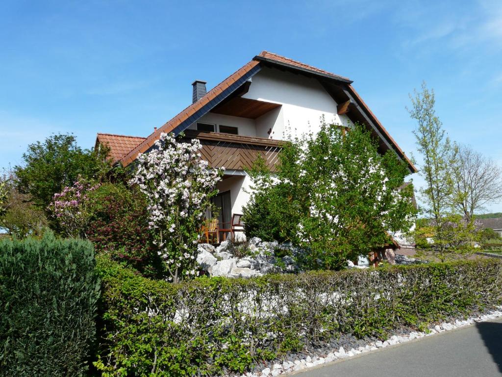 uma casa branca com arbustos floridos à sua frente em Ferienwohnung Udo und Stefani Laux em Berg