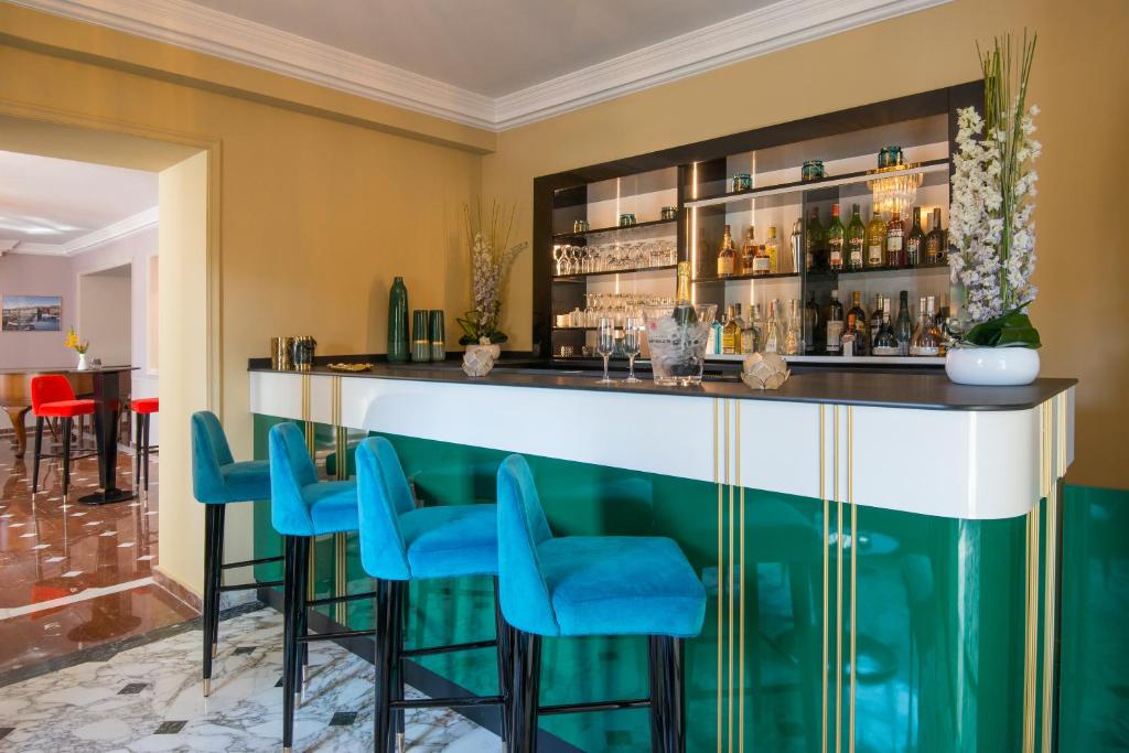 a bar with blue chairs in a room at Hotel Carlton in Beaulieu-sur-Mer