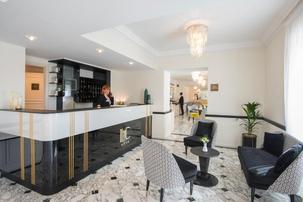 a woman standing at a bar in a living room at Hotel Carlton in Beaulieu-sur-Mer