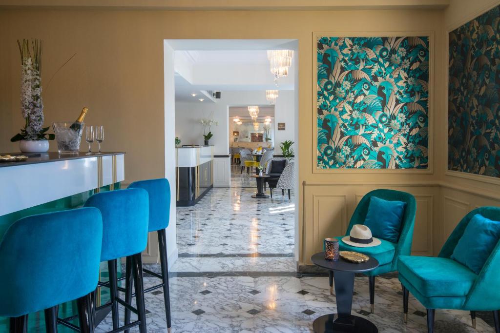 a lobby with blue chairs and a bar at Hotel Carlton in Beaulieu-sur-Mer