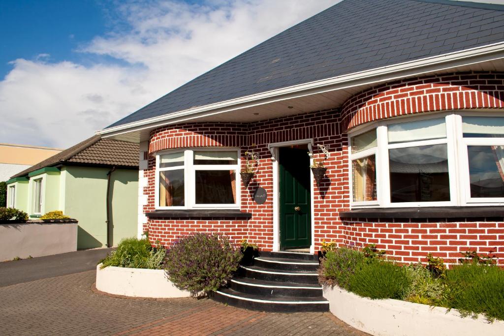 una casa de ladrillo rojo con una puerta verde en Lissadell Holiday Apartment, en Buncrana