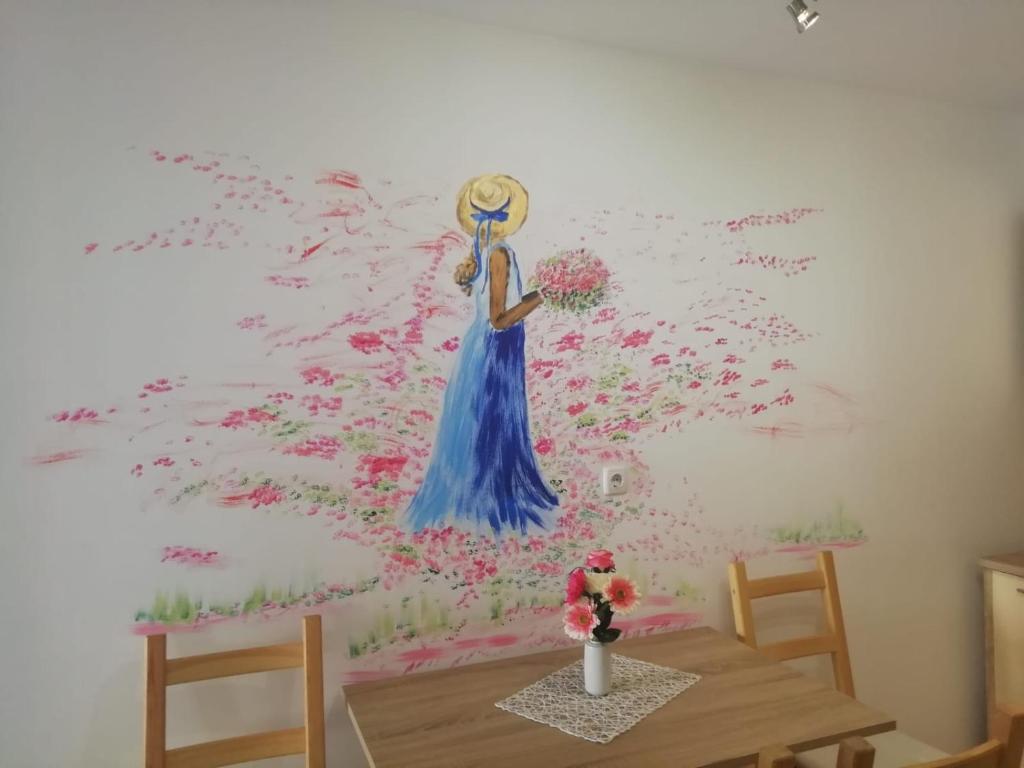 una pintura de una mujer con un vestido azul en una pared en Studio Rose en Pula