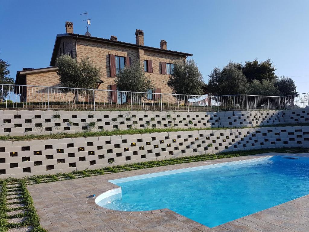 a swimming pool in front of a brick wall at Agriturismo bio Verde Armonia in Montemarciano