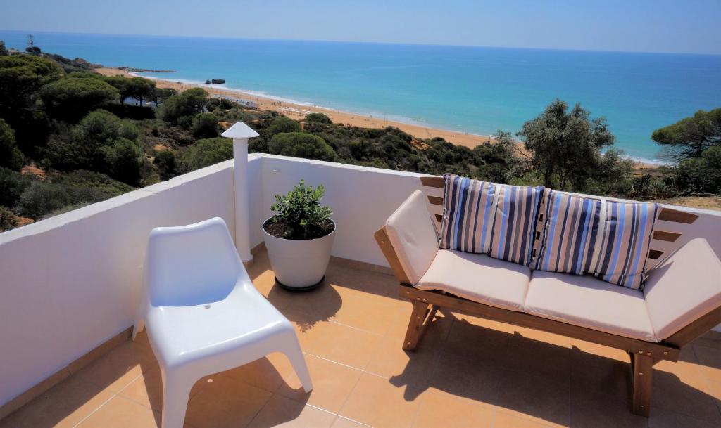 uma cadeira branca e uma cadeira numa varanda com o oceano em Golden Cliff House em Albufeira