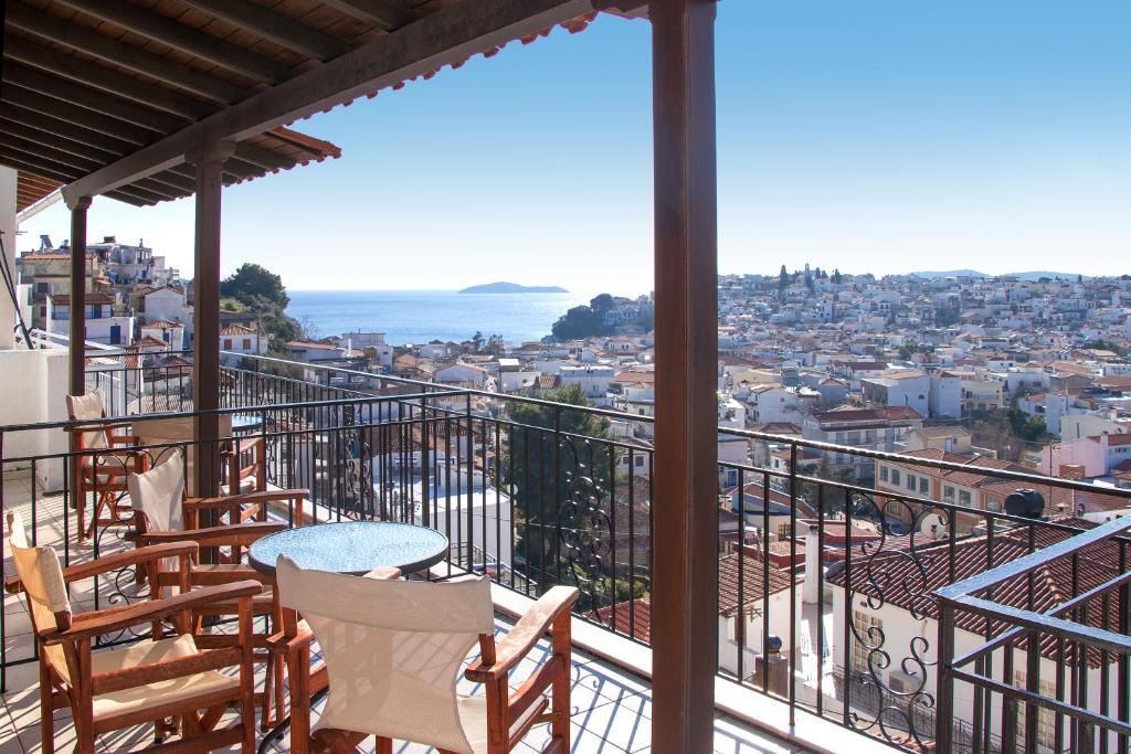 a balcony with chairs and tables and a view of the city at Stefanis House in Skiathos