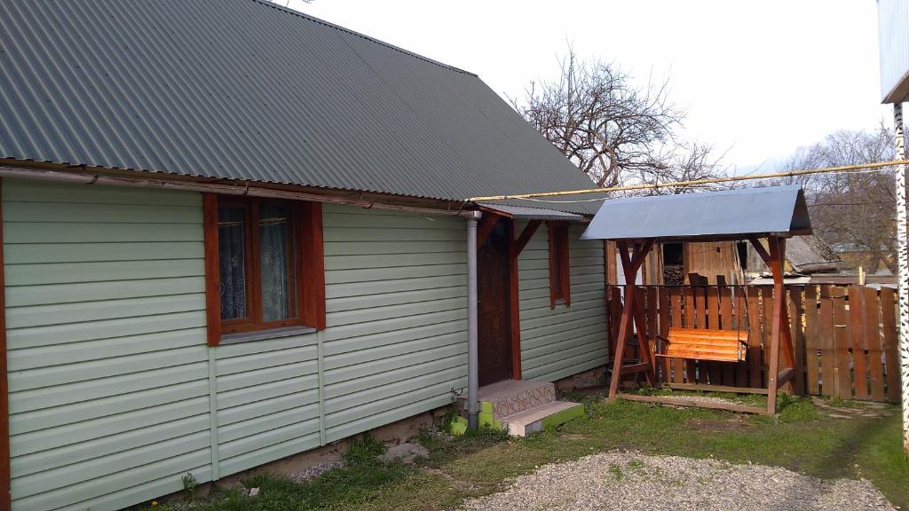 une maison avec une terrasse couverte et un banc en bois dans l'établissement Базилік Люкс, à Yaremtche