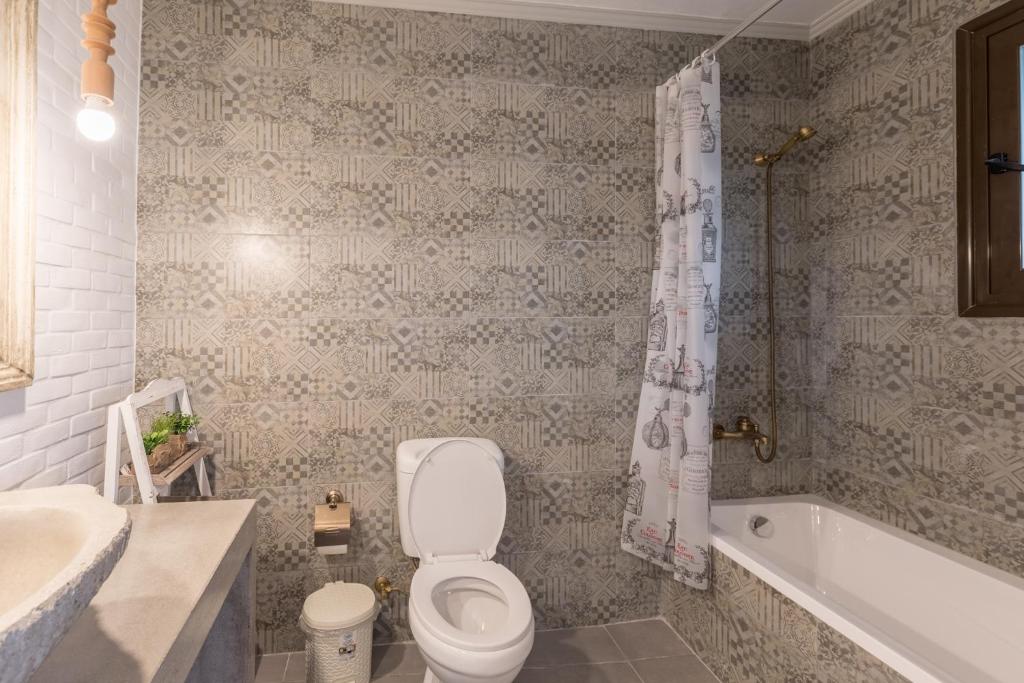 a bathroom with a toilet and a tub and a sink at Olympus Studios in Malia
