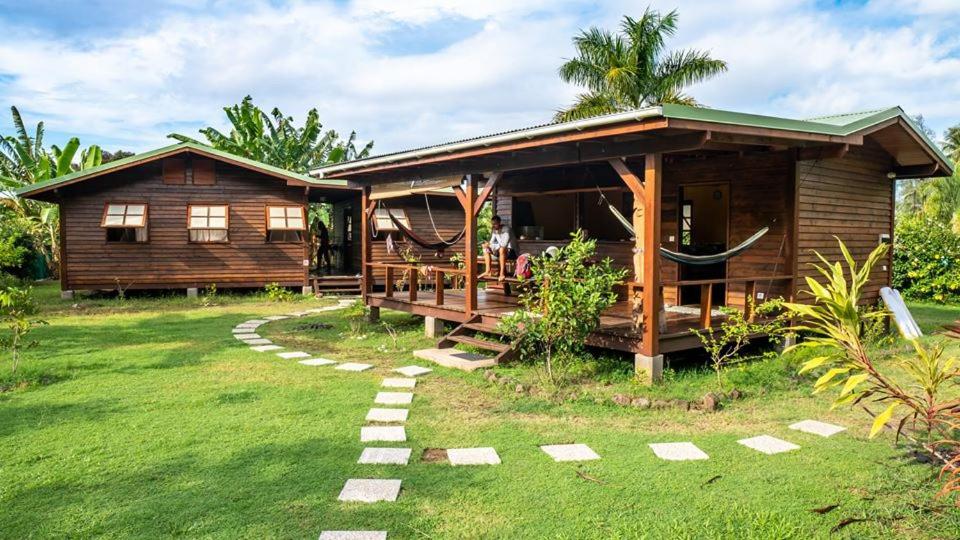 
a small house with a wooden roof and grassy area at PainaPaopao Backpacker in Moorea
