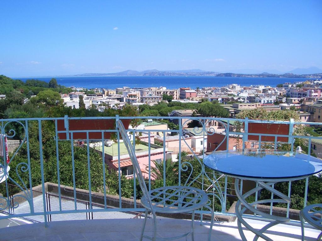een balkon met een tafel en stoelen en uitzicht op de stad bij Posidonia Residence in Ischia