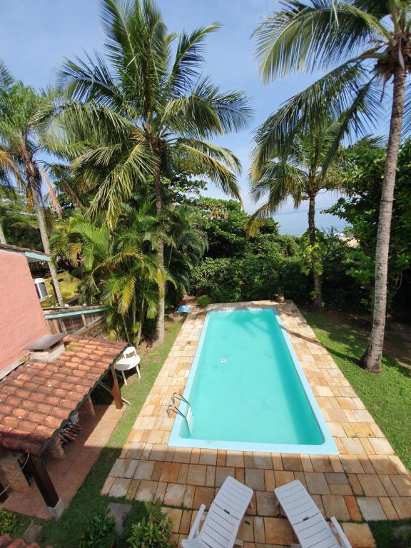 een zwembad met 2 stoelen en palmbomen bij Casa pé na areia em Toque Toque in São Sebastião