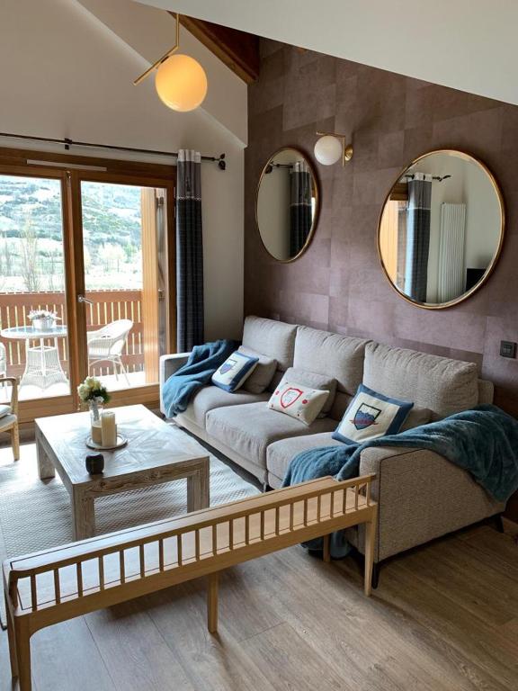 a living room with a couch and a table and mirrors at Tuca del Mont in Benasque