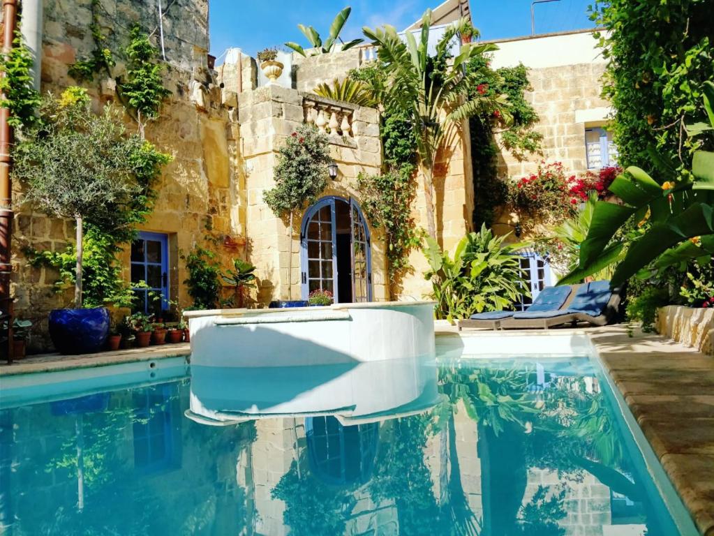 uma piscina com um barco branco em frente a um edifício em Il Kiostro em Żurrieq