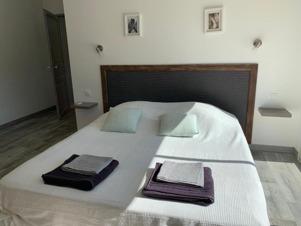- un grand lit blanc avec 2 serviettes dans l&#39;établissement Le Mazet Des Joncs en Provence, à Saint-Pierre-de-Vassols