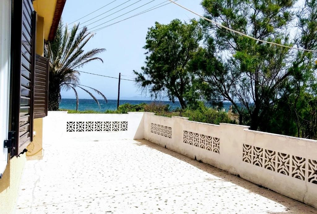 una cerca blanca con vistas al océano en Summerhouse Peggy: close to Athens airport by the sea en Loútsa