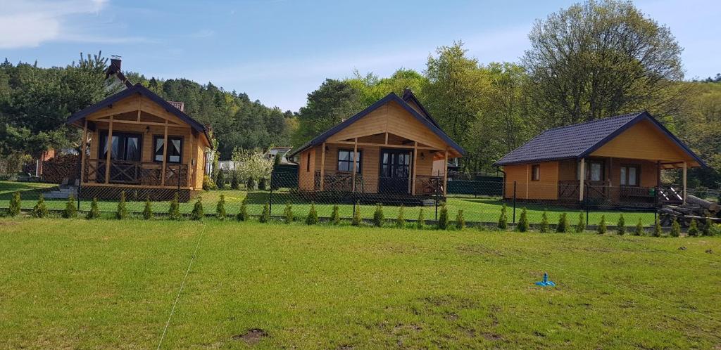 dwa drewniane domki na polu z płotem w obiekcie CICHOsza w mieście Lubkowo
