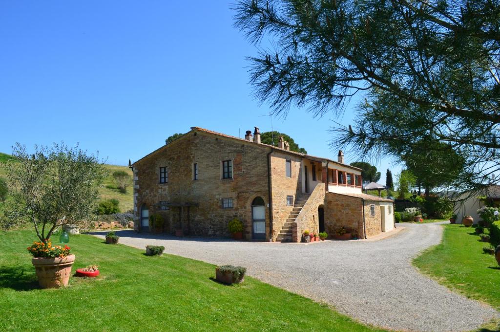 una vieja casa de piedra en un camino de grava en Agriturismo Poderino en San Quirico dʼOrcia