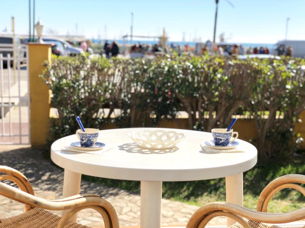 a white table with two cups and two chairs at Apartament amb jardi a la platja d'Empuriabrava in Empuriabrava