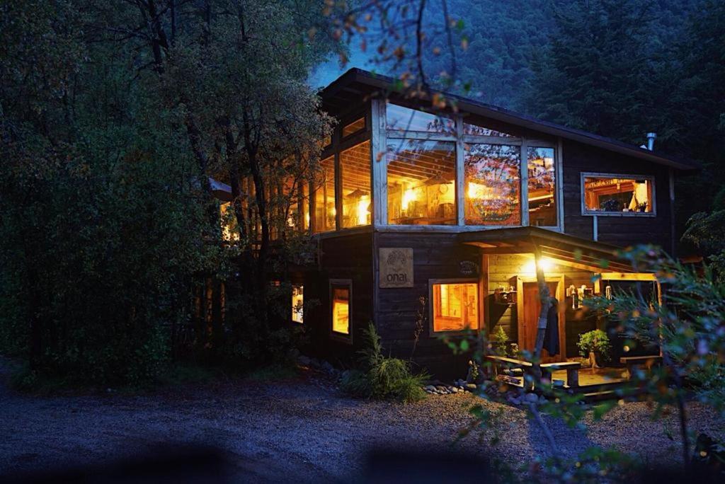 a house with lights in the windows at night at Onai Hostel in Las Trancas