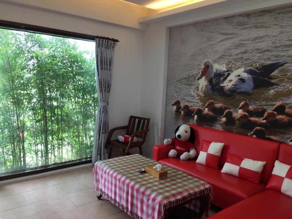 a living room with a red couch and a large window at Beautiful Yilan Resort in Dongshan