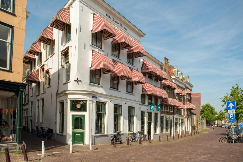 a white building with a green door on a street at City Hotel Nieuw Minerva Leiden in Leiden