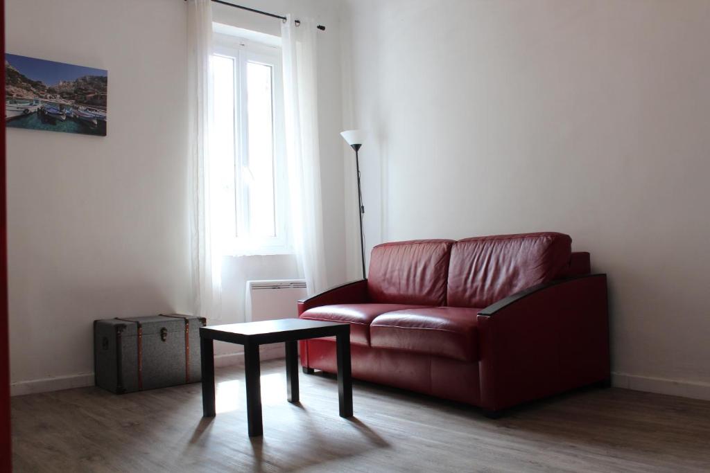 sala de estar con sofá rojo y mesa en L'Éphémère Canebière - Gambetta, en Marsella