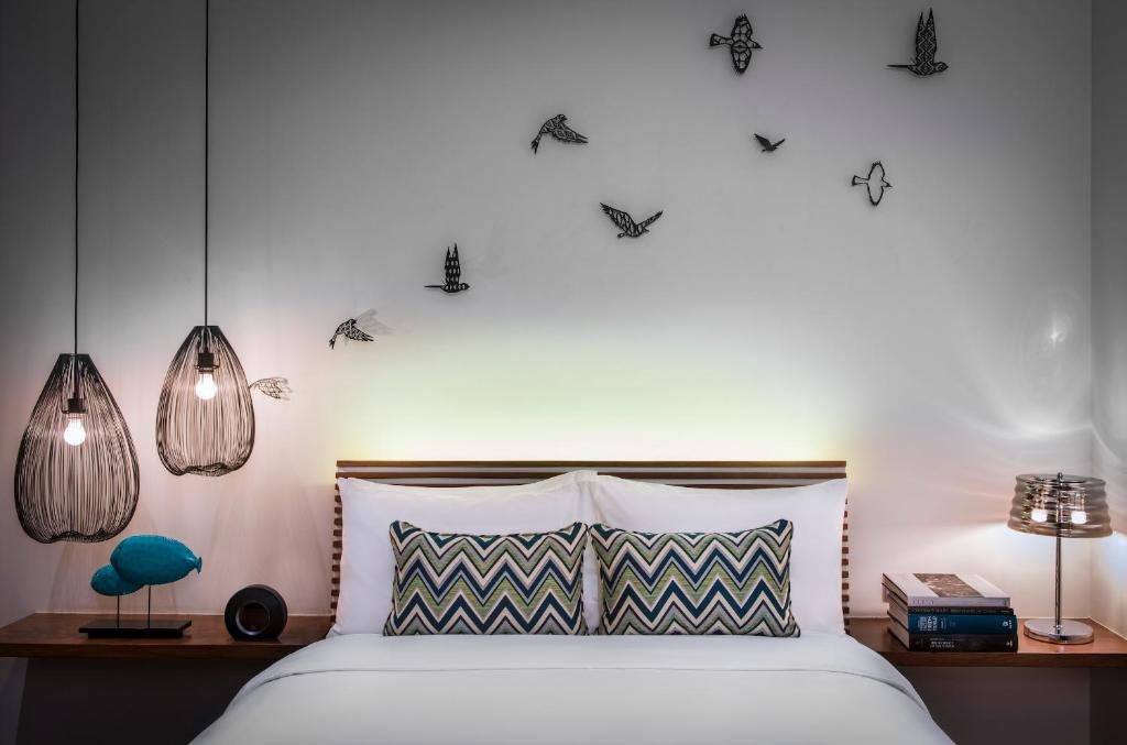a bedroom with a bed with two lamps and two tables at The Aviary Hotel in Siem Reap