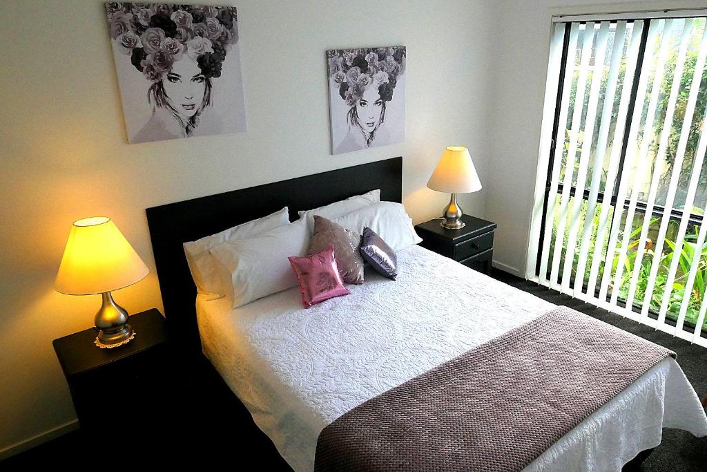 Un dormitorio con una cama con dos lámparas y una ventana. en Corlette Retreat, en Corlette