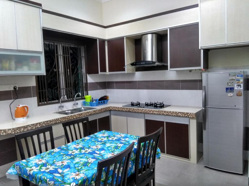 uma cozinha com uma mesa com cadeiras e um frigorífico em Muslim 2 Stay em Malaca