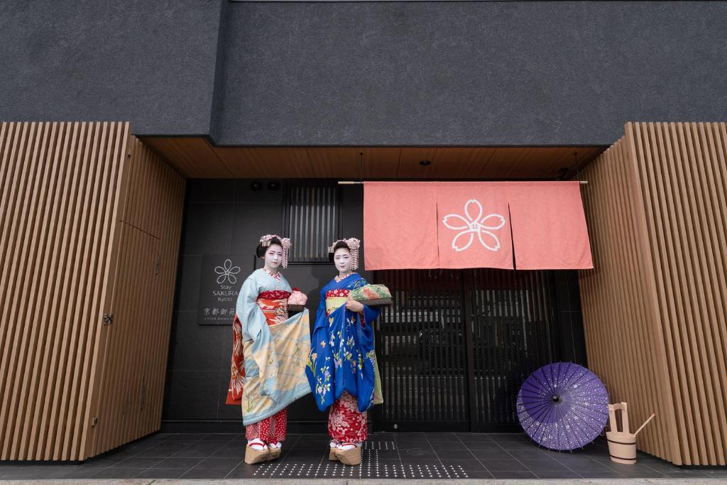 deux femmes en kimonos debout devant un bâtiment dans l'établissement Stay SAKURA Kyoto Gyoen East, à Kyoto