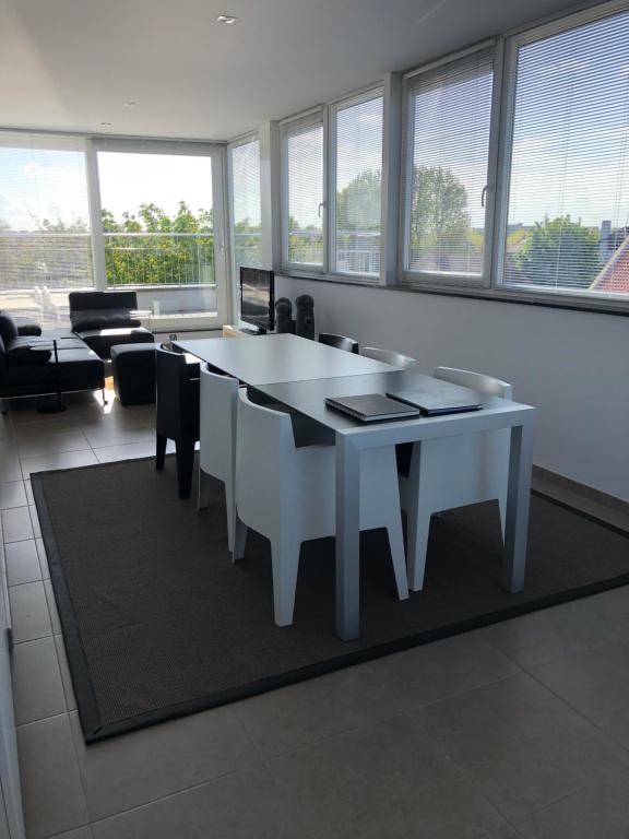 un tavolo bianco con sedie in una stanza con finestre di Residentie Kapelhof a Koksijde