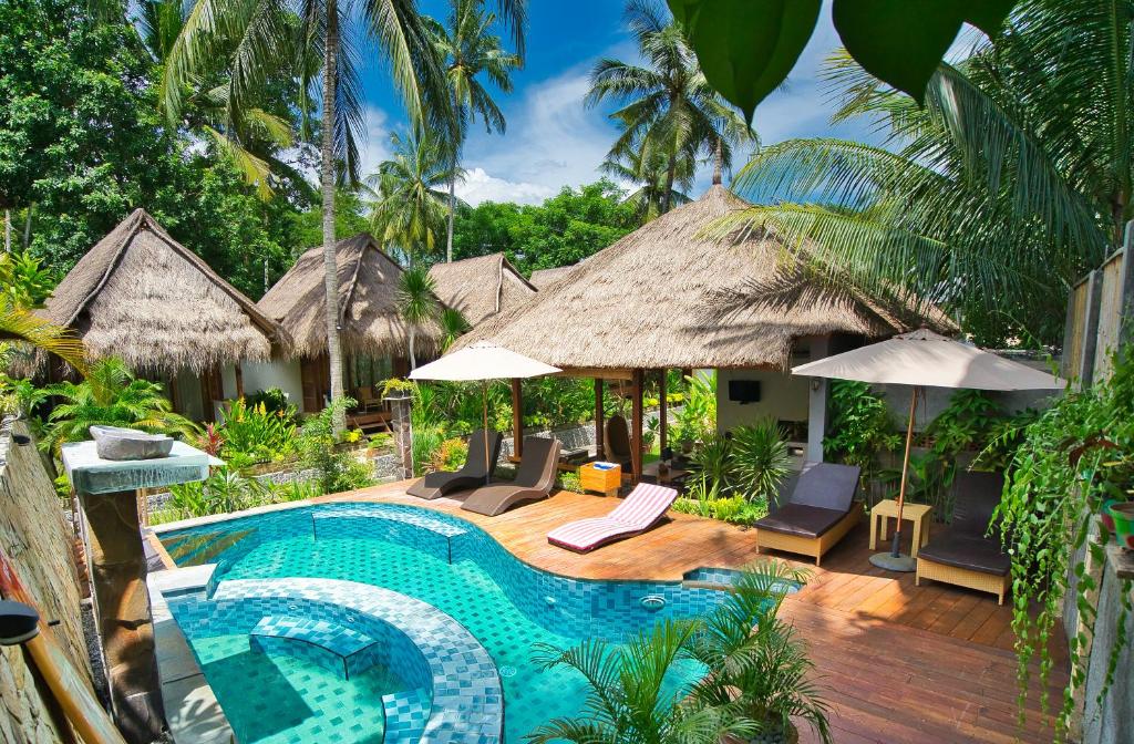 un resort con piscina attrezzata con sedie e ombrelloni di Village Vibes Lombok a Kuta Lombok