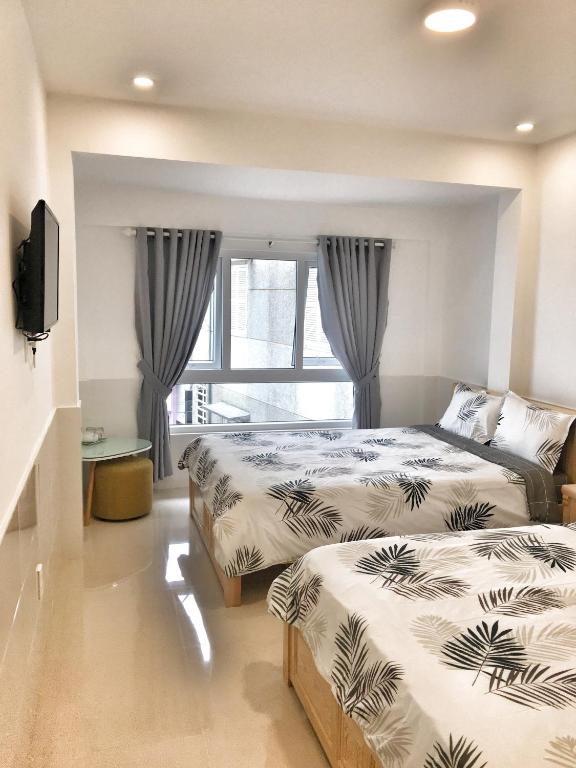 una camera da letto con due letti e una finestra di Hoang Vu Guest House a Da Lat