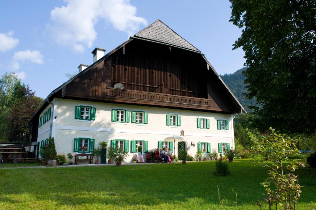 a large white house with a wooden roof at Naturresort FiSCHERGUT - Lodge Wolfgangthal in St. Wolfgang