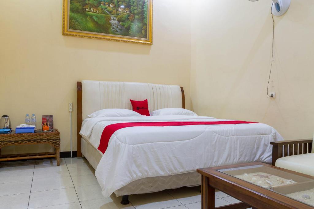 - une chambre avec un grand lit blanc et un oreiller rouge dans l'établissement RedDoorz @ Pataruman Garut, à Garut