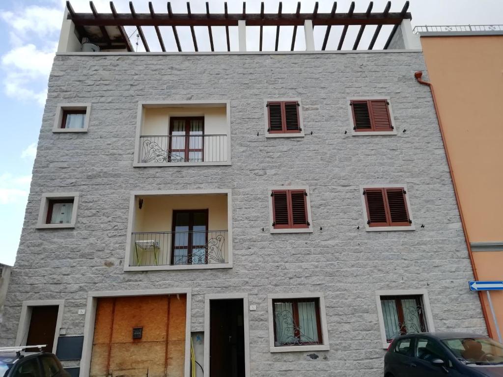 un edificio gris con persianas y ventanas rojas en B&B Nino, en Olbia