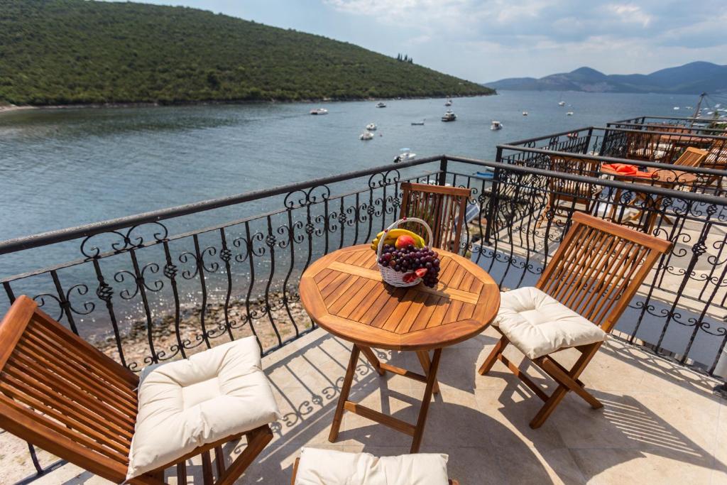 een tafel en stoelen op een balkon met uitzicht op het water bij Villa SAN Apartments in Tivat