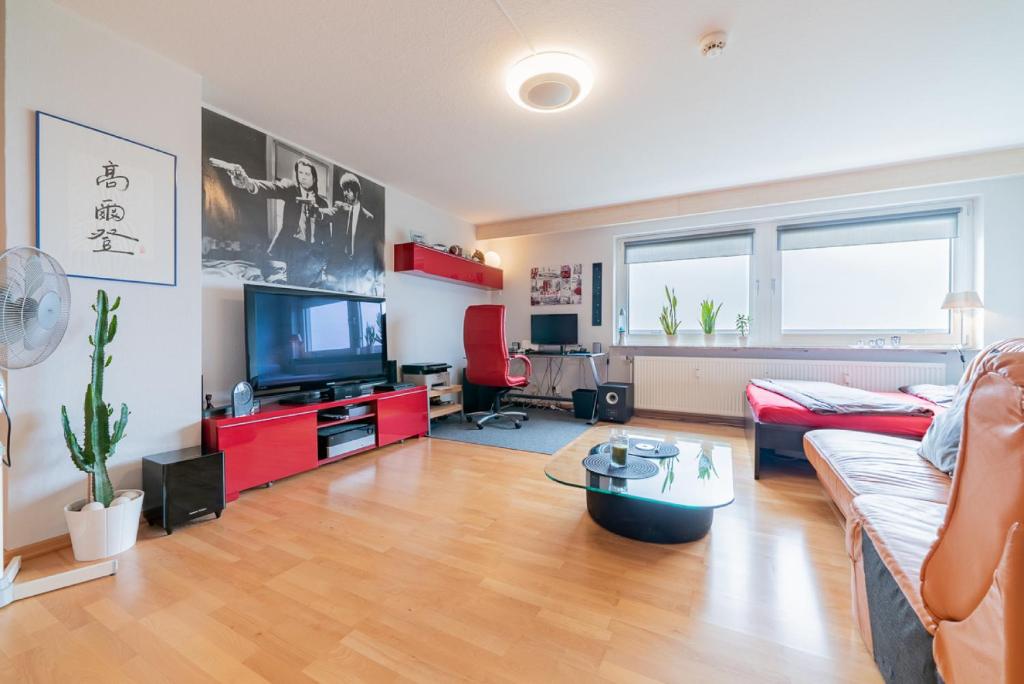 sala de estar con sofá y TV en Private Rooms en Hannover