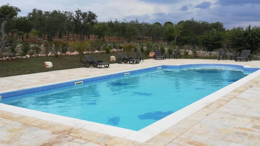 a swimming pool with blue water in a yard at Eremo del Dottó in Alberobello