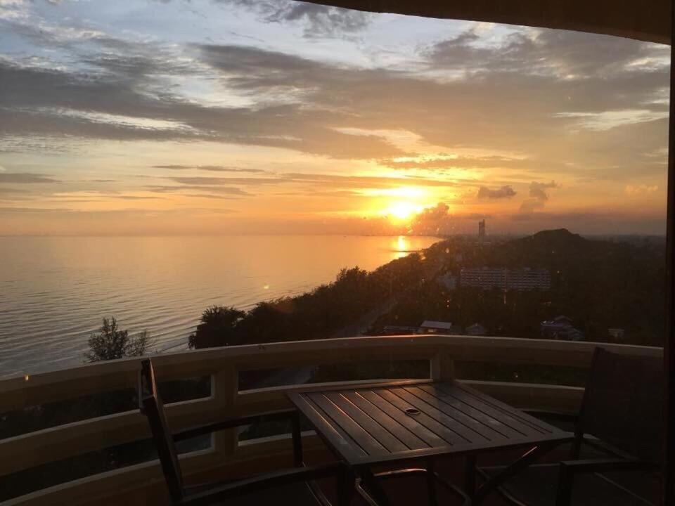 - un coucher de soleil sur l'océan avec une table en bois sur le balcon dans l'établissement VIP CONDO RAYONG 343, à Rayong