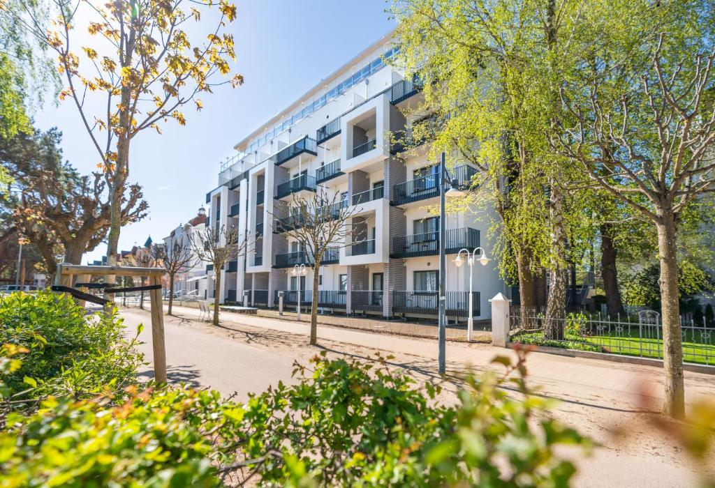 an apartment building on a street with trees at Strandhotel Ahlbeck, a member of Radisson Individuals in Ahlbeck