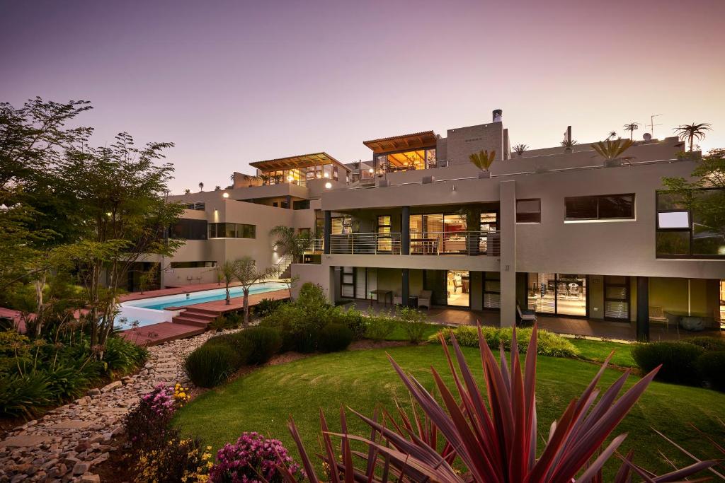 a large house with a garden and a swimming pool at Dynasty Forest Sandown Self Catering Hotel in Johannesburg