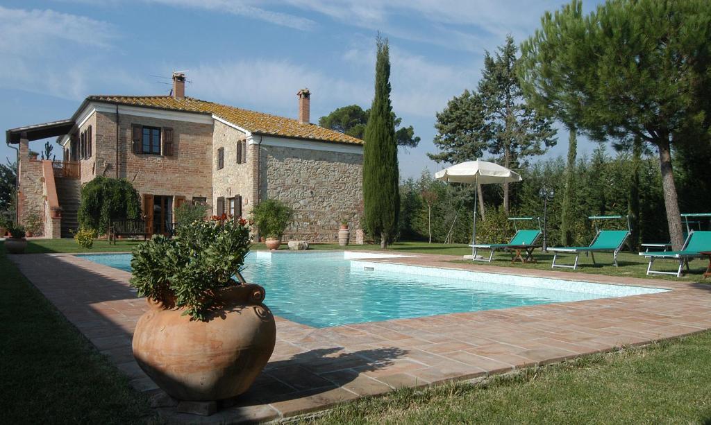 une maison et une piscine avec une plante dans un pot dans l'établissement VILLA VITELLINO, à Castiglione del Lago