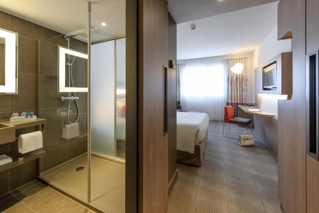 a hotel room with a bed and a bathroom at Novotel Lugano Paradiso in Lugano