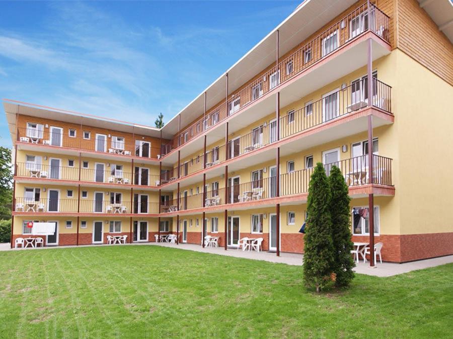 a large building with tables and chairs in a yard at Beluga in Šventoji