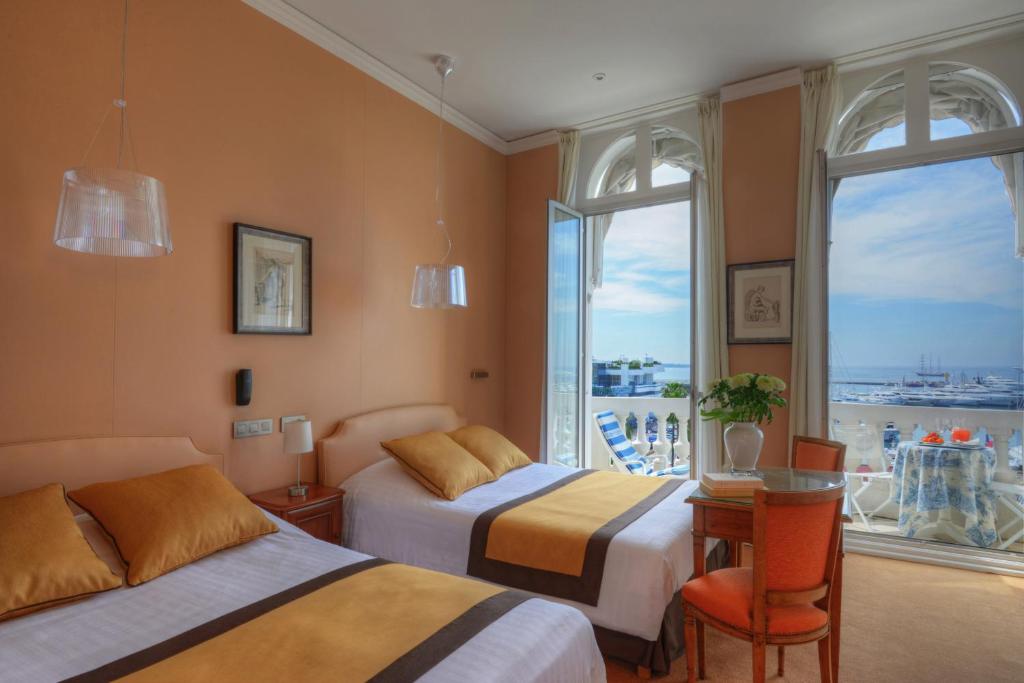 a hotel room with two beds and a table and chairs at Hotel Splendid in Cannes