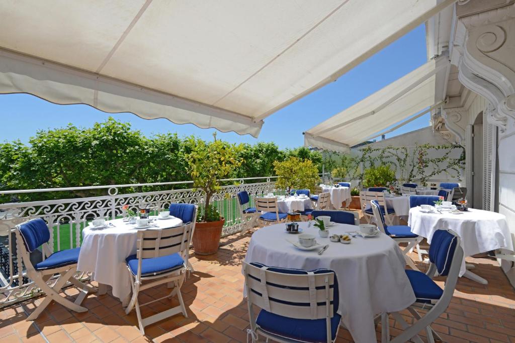 a restaurant with white tables and blue chairs at Hotel Splendid in Cannes