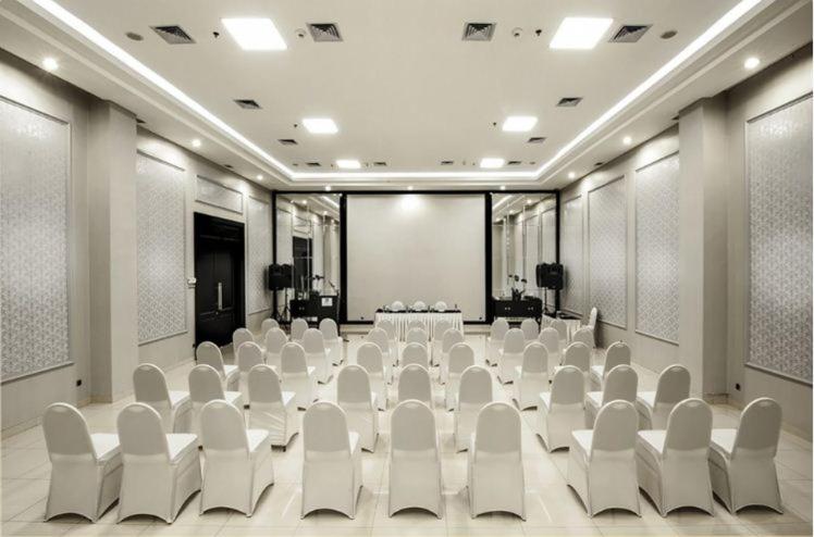 una sala conferenze con sedie bianche e un palco di Hotel Permata Bogor a Bogor